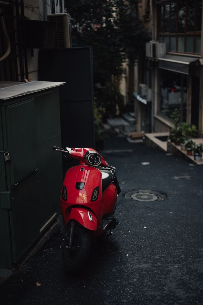 why-choose-us A vibrant red scooter parked in a moody, narrow alley in Istanbul's Beyoğlu district.